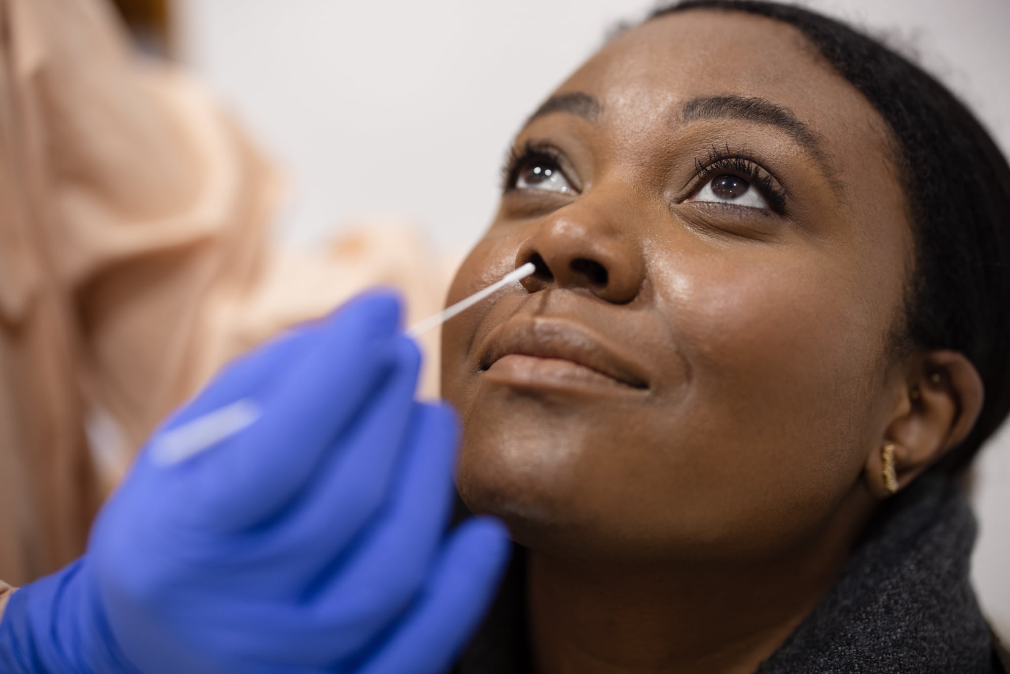 Young woman undergoing a corona antigen test with a cotton swab entering her nose