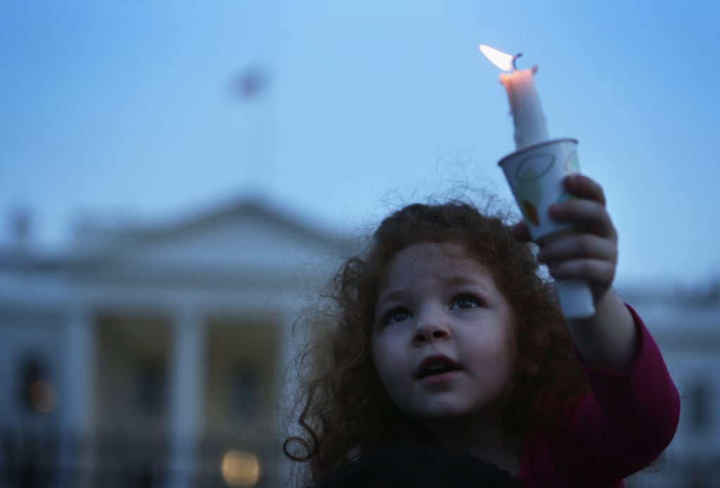 A little girl held up a candle during a vigil in front of the White