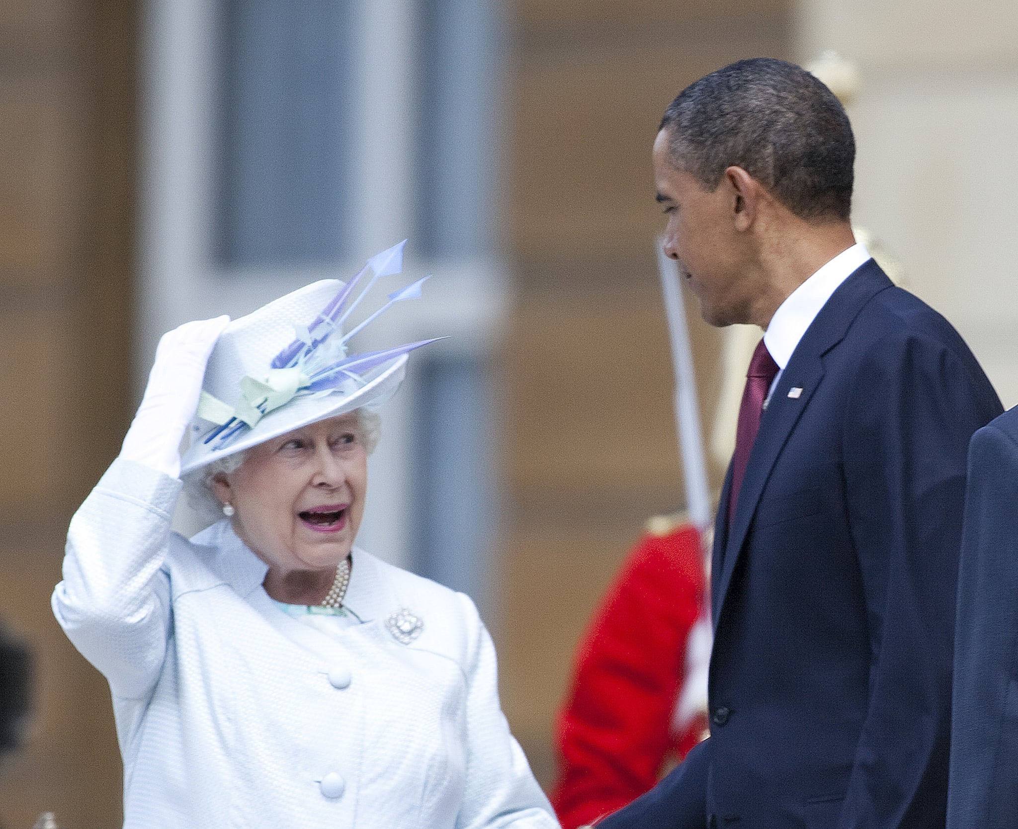 Queen Elizabeth II adjust her hat and talks to U.S. President Barack Obama in 2011