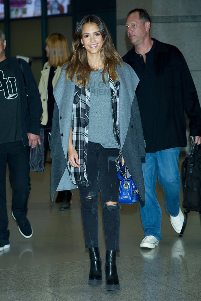 Jessica Alba layered up for her flight but didn't hide her cool-girl tee, plaid, or bright bag.