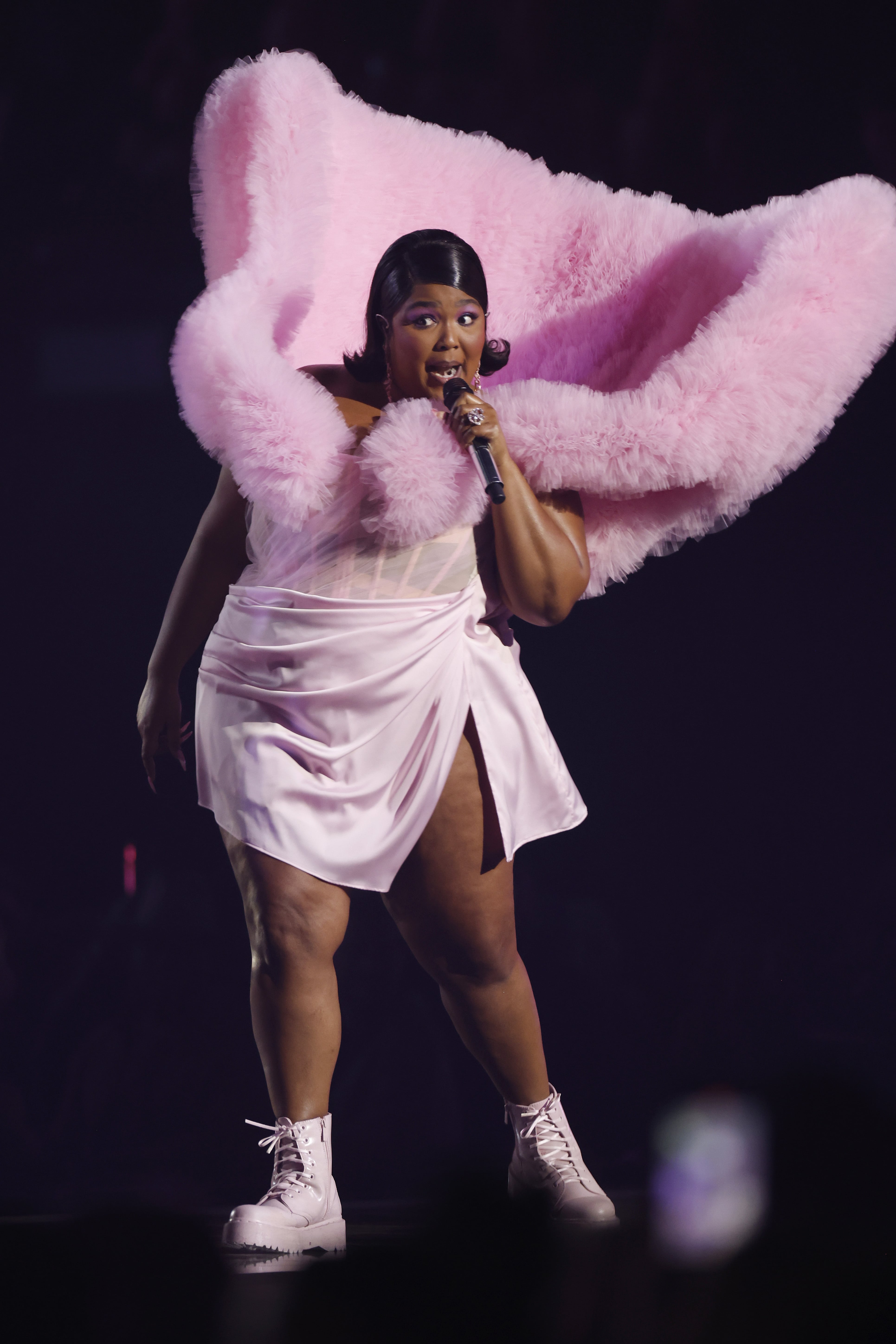 lizzo in pink dress Lizzo makes a bold entrance in a hot pink feathered coat over a shimmering pink  gown, finished with a playful oversized bow