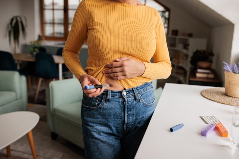Woman applies an IVF treatment injection to her stomach while at home.