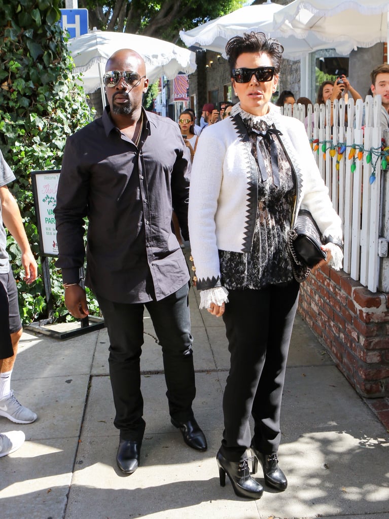 Kris Jenner stood tall in black skinny jeans, lace-up booties, and a lacy high-neck blouse. Her white cardigan, lined with leather, topped her outfit and complemented her Chanel bag and dark sunglasses.