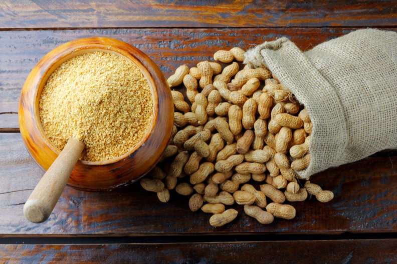 Jar of peanut butter powder next to a burlap sack of peanuts