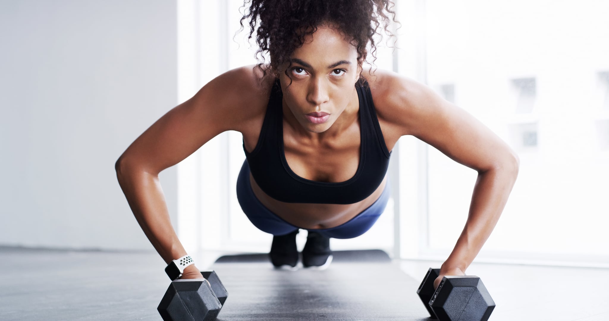 Shot of a young woman working out with dumbbells in a gym