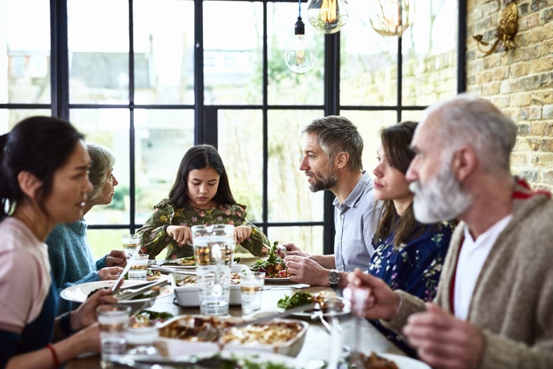 Social gathering between grandparents, adult offspring and pre teen granddaughter, sitting and eating dinner around dining room table, enjoying spending quality time over a leisurely meal, relaxed and friendly