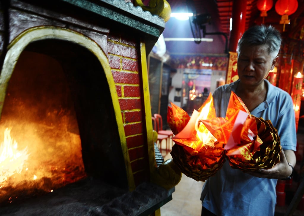 A man burned papers while praying at Hong San Ko Tee Temple in Surabaya, Indonesia.