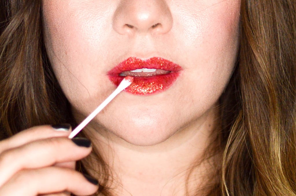 The best and easiest way to apply glitter (without fallout) is to use a slightly damp cotton swap. I'd recommend using a fine glitter pigment; both MAC and NYX sell affordable options. Here, I'm using MAC Glitter in Reflects Rust ($22), a sparkling warm red.
To apply, dump a little glitter onto a plate and dip the cotton swap to pick up pigment. Once a good amount of glitter is on the swap, lightly touch to lips making sure not to apply too much!