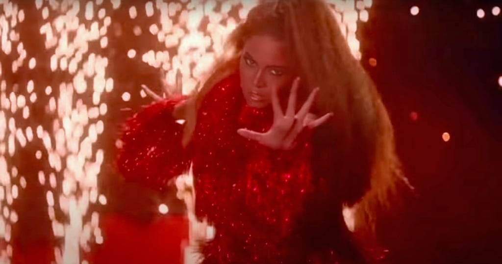 Beyoncé wears a red fringed dress.
