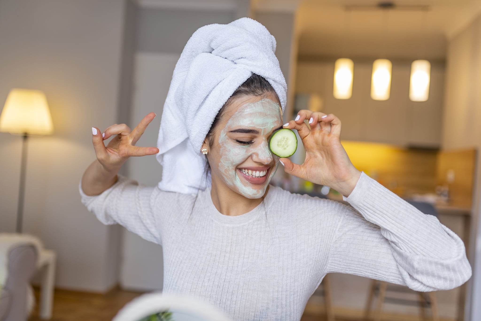 Portrait of a happy caucasian woman using natural secrets to do a skin care. Natural homemade facial masks. Beautiful young woman applying avocado facial mask with cucumber