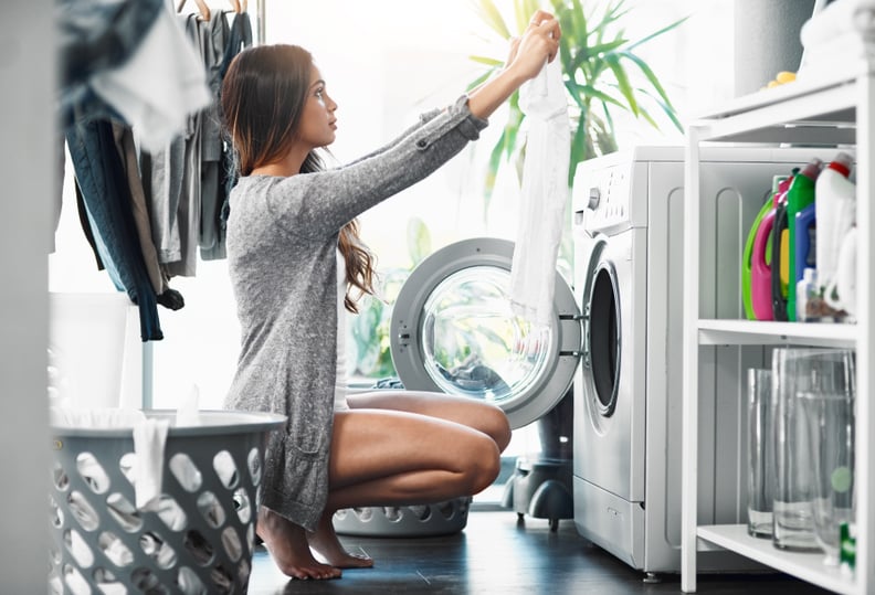 Full length shot of an attractive young woman doing her laundry at home