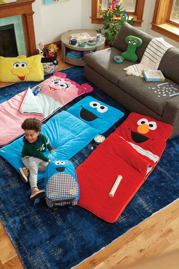 Furry Big Bird Sleeping Bag ($129), Furry Abby Cadabby Sleeping Bag ($129), Furry Cookie Monster Sleeping Bag ($129), Furry Elmo Sleeping Bag ($129), Letter I Throw Pillow ($29), and Cookie Monster Rolling Luggage ($59)