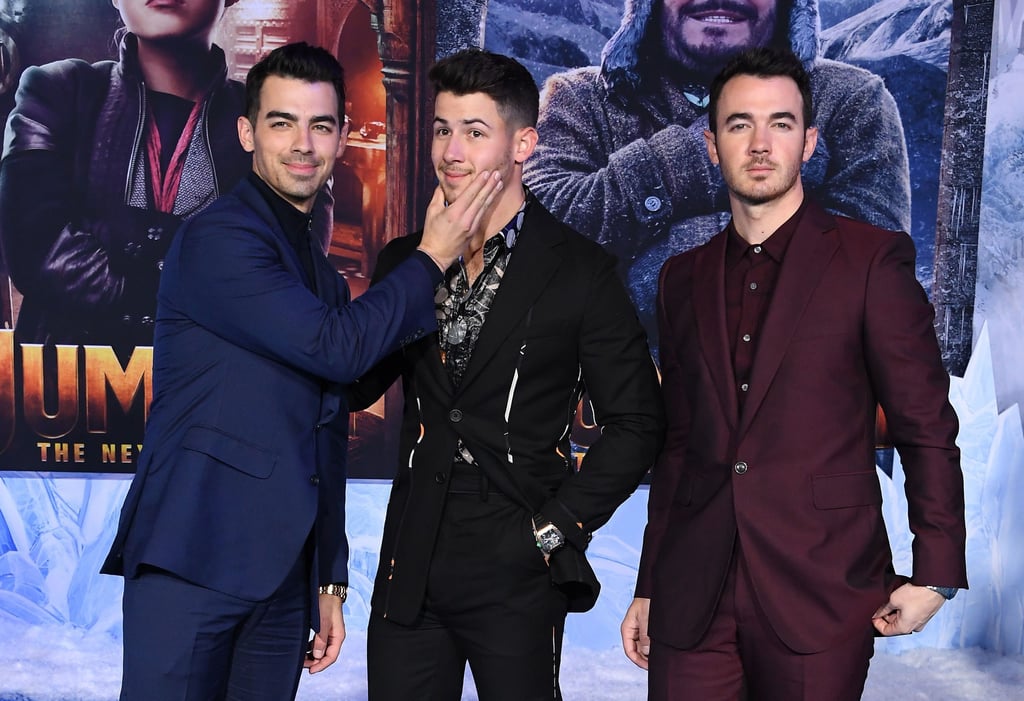 The Jonas Brothers were in full force as they attended the premiere of Nick's upcoming movie, Jumanji: The Next Level, in LA on Monday. Looking incredibly dapper in similar suits, the brothers were all smiles as they walked the blue carpet together. At one point, Joe teased his little brother by playfully smushing his face for the cameras. 
Turns out, Kevin and Joe were stepping in for Nick's wife, Priyanka Chopra, who unfortunately couldn't attend due to filming. "She's in India right now, shooting a movie there," Nick told Entertainment Tonight during the premiere. "Although she's jealous because she loves Jumanji. She loved the last one. And she really wanted to be here, but she's got work." Even though we didn't get any cute moments between Nick and Priyanka during the premiere, the rare Jonas Brothers appearance totally makes up for it. See more pictures from the premiere ahead.