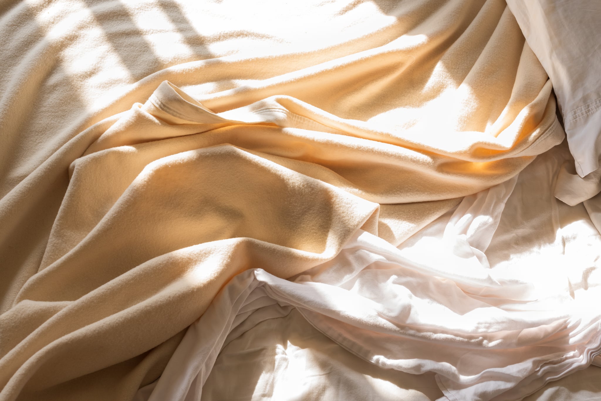 unmade bed in morning sunlight
