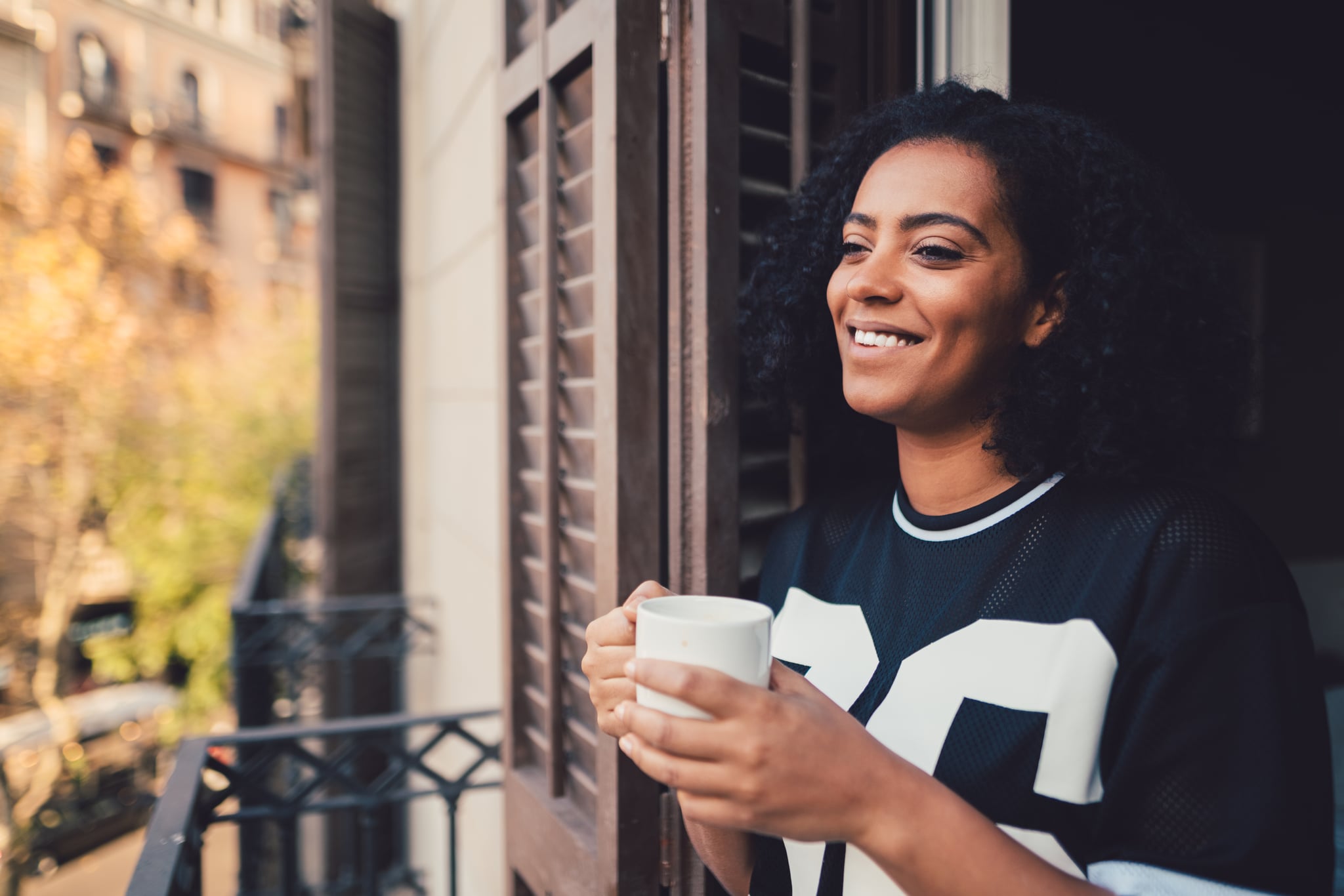 Smiling woman in Barcelona enjoying a cup of coffee at the balcony