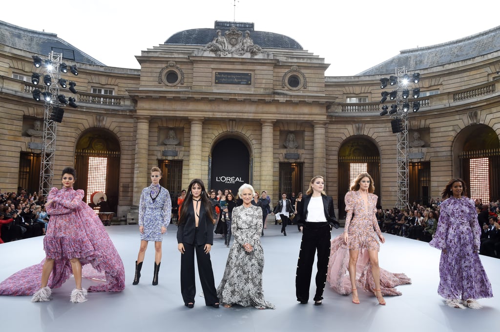 Camila standing on the "Le Defile L'Oreal Paris" fashion show stage beside (from right to left) Aishwarya Rai, a L'Oréal model, Helen Mirren, Amber Heard, Doutzen Kroes, and Liya Kebede.
