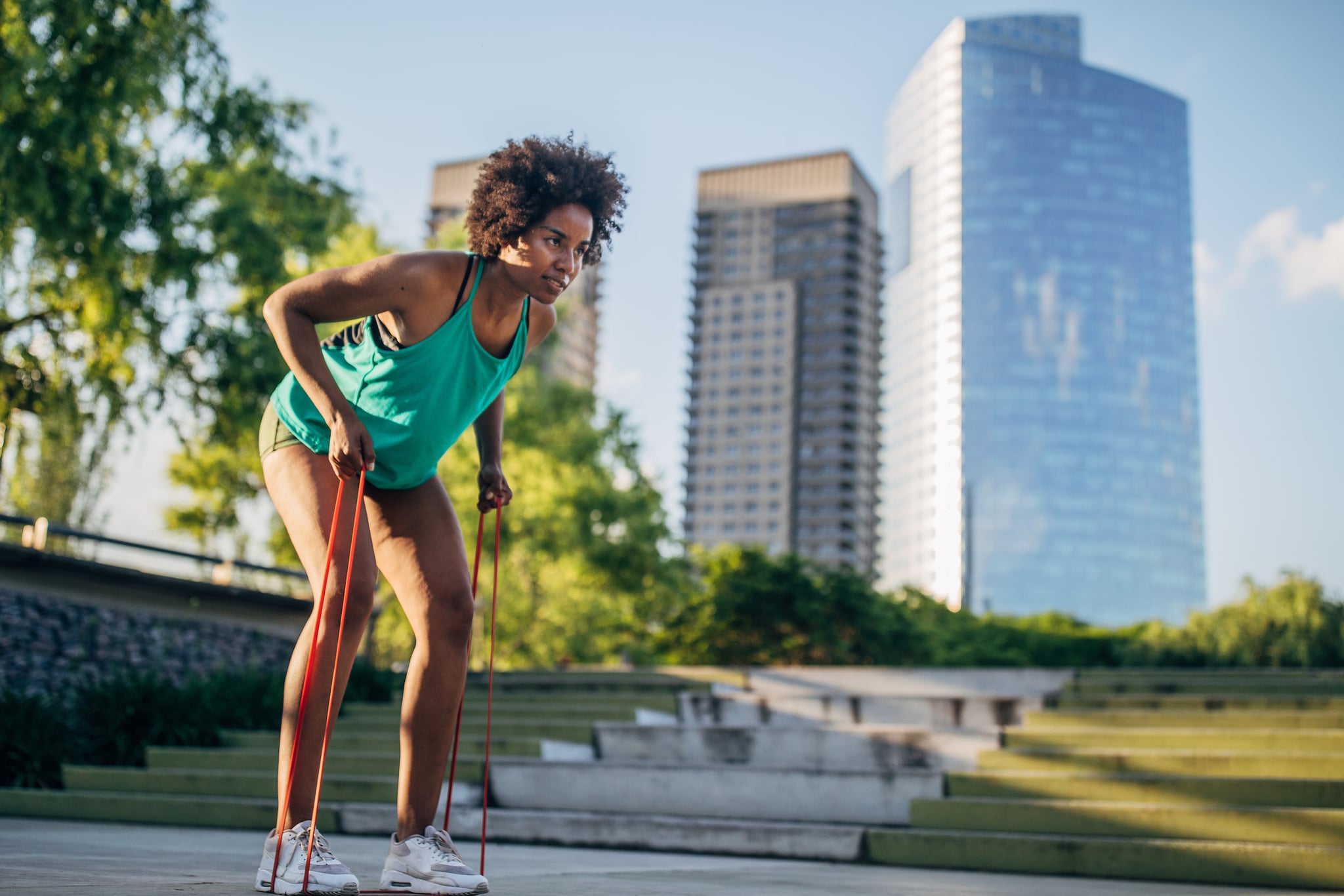 Beautiful young woman exercising outdoor with resistance band