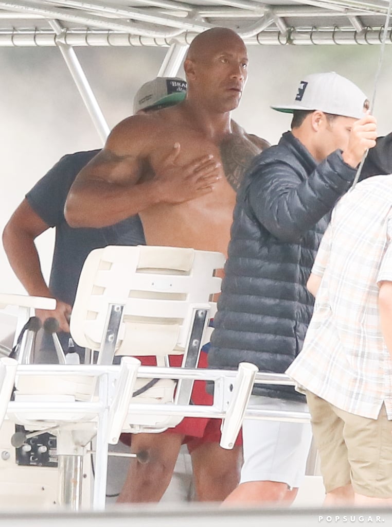It's almost as if Dwayne Johnson's muscles get bigger by the second. On Monday, the actor put his buff physique on display on the Georgia set of Baywatch. On top of whipping his shirt off for the cameras, Dwayne showed off his impressive lifeguard skills while rescuing a man from a burning boat. Also on set were his costars, Zac Efron and Alexandra Daddario, who kicked off filming scenes for the '90s series adaptation in February. 
When Dwayne isn't busy shooting Baywatch, he's at home being a doting father to his daughters, 4-month-old Jasmine and 14-year-old Simone. Over the weekend, he made hearts swell when he took to Instagram to share a heart-melting birthday message for his baby girl. He also brought Simone as his date to the MTV Movie Awards earlier this month. Keep reading to see more of Dwayne, and then check out all the reasons we love him.