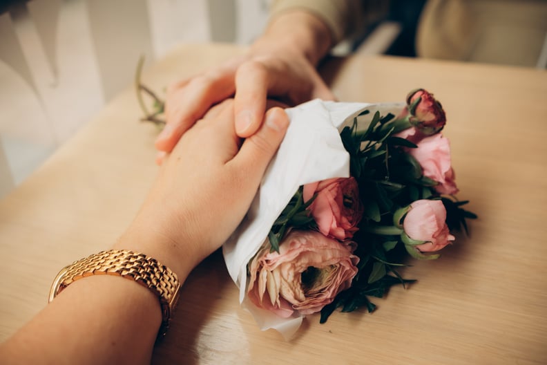 hands of a couple in love on a bouquet of flowers