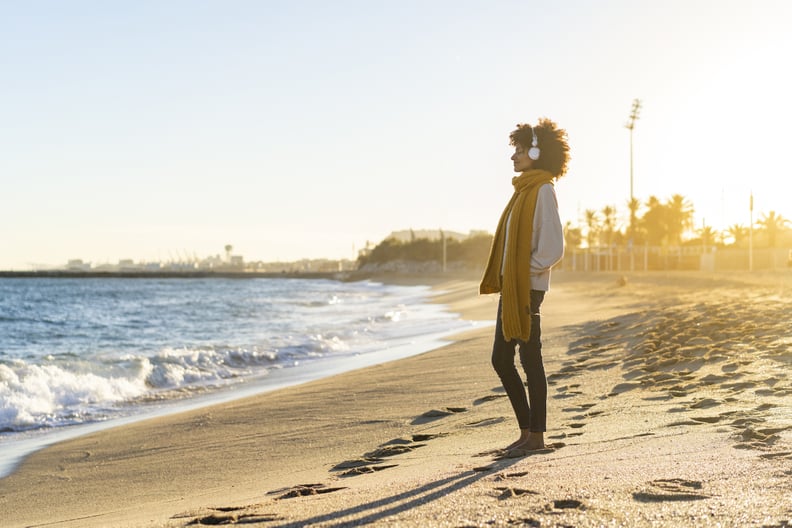 Woman at the beach, wearing headphones, listening music