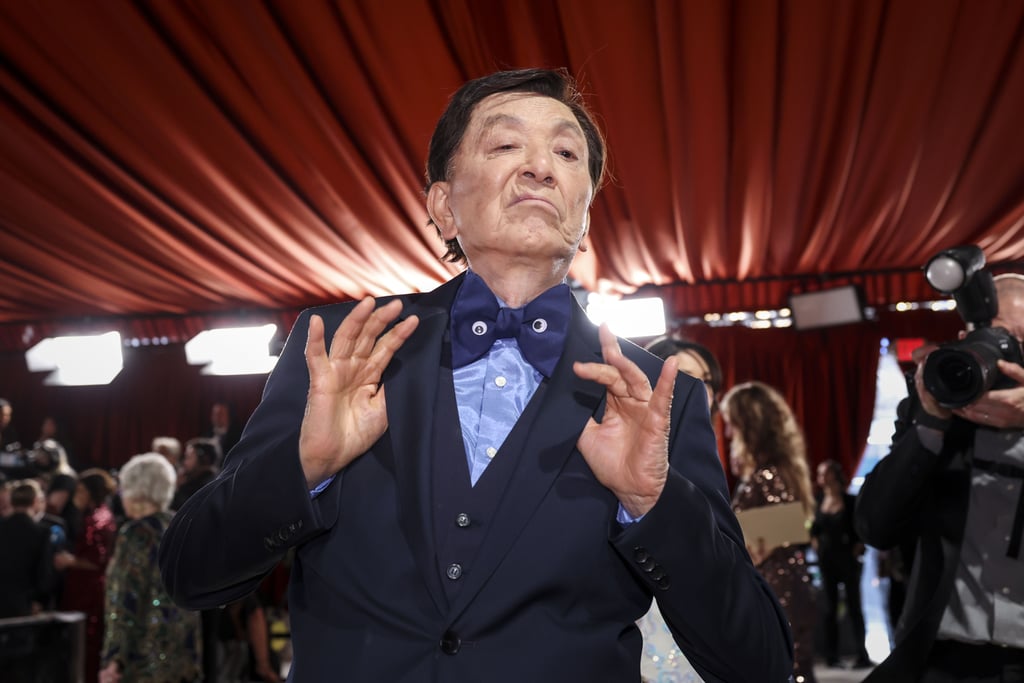 Acting your age is overrated. At 94 years old, James Hong brought the best energy to the red carpet at the 2023 Oscars, striking fabulous poses and pulling funny faces for the cameras. As he made his way through the venue, the legendary actor raised his hands into peace signs, stuck his tongue out at onlookers, and spread joy to everyone who crossed his path. On a night typically characterized by pomp and circumstance, his light-hearted appearance was a welcome reminder not to take anything too seriously. 
Although he had evidently taken the night off from multiverse jumping, upon closer inspection, some of Hong's poses featured an unconventional bowtie, which he had embellished with two small googly eyes. Fans of the film might recognize this subtle reference to "Everything Everywhere All At Once," which is nominated in a whopping 11 categories. In the movie, googly eyes come to symbolize the importance of enjoying the present moment. As proven through his red carpet appearance, Hong could not have embraced this message more wholeheartedly. 
Later on, Hong reunited with some of his fellow cast members, including Jamie Lee Curtis, who gave him a kiss on the cheek inside the theater. Curtis previously shared her reaction to the movie's many nominations, expressing her genuine surprise. Other costars, like Michelle Yeoh also weighed in on the historic accomplishment, saying, "Every single person who worked on this film poured their heart and soul into it, and we are all so grateful to the Academy for recognizing so many from our 'EEAAO' family." Read on to see how Hong paid tribute to the film in his own, fantastic way. 

    Related:

            
            
                                    
                            

            The "Top Gun: Maverick" Cast Showed Up in Full Force For an Epic Reunion at the Oscars