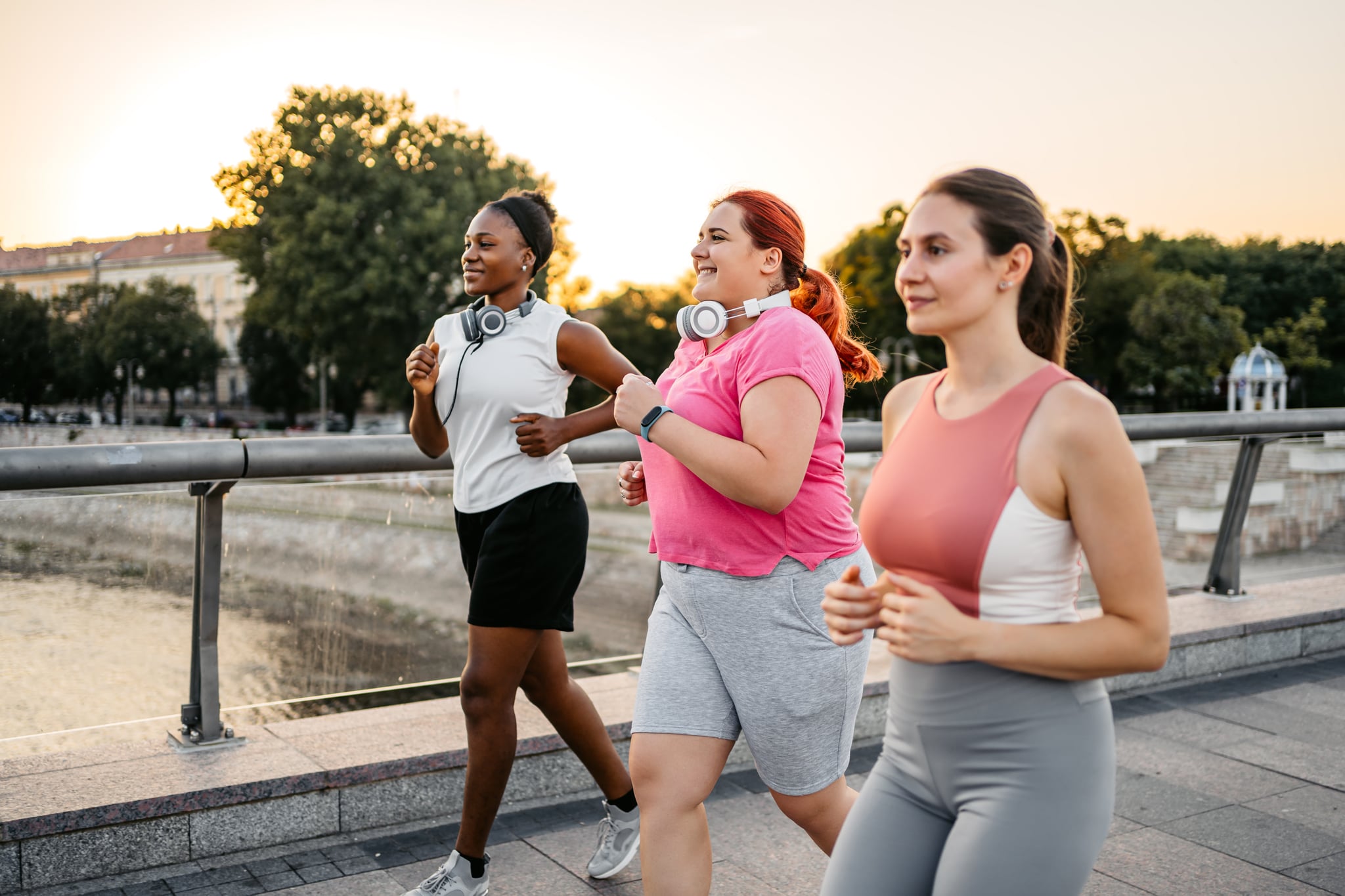 Three young female friends jogging on the bridge together, group cardio.