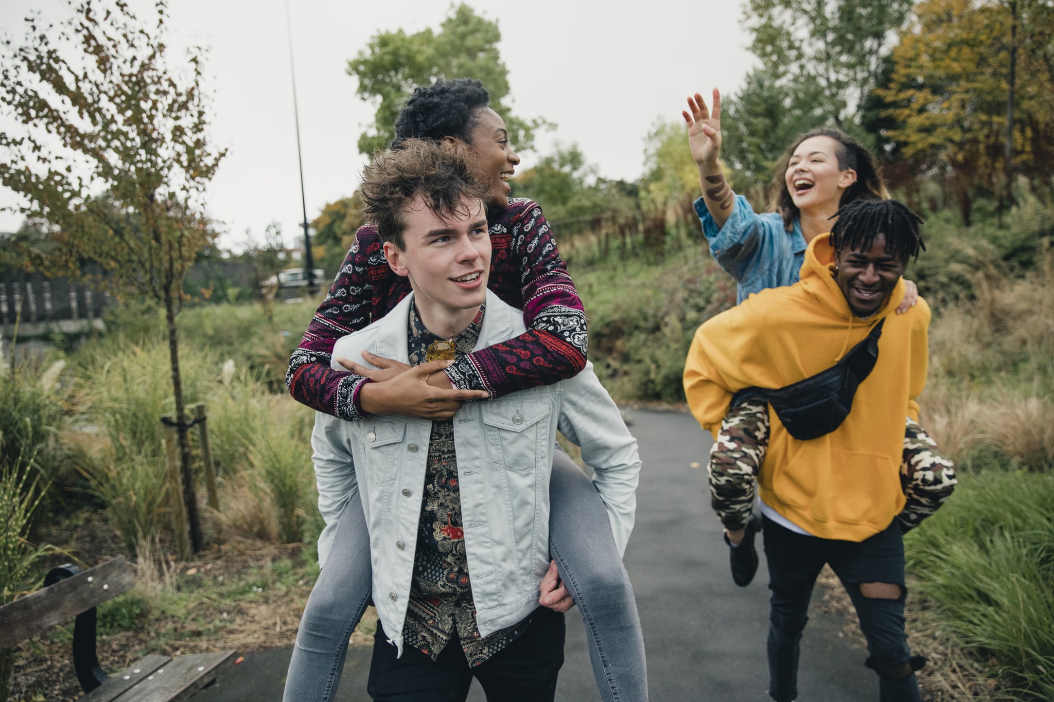 Two young men are racing through the park with their girlfriends on their backs.