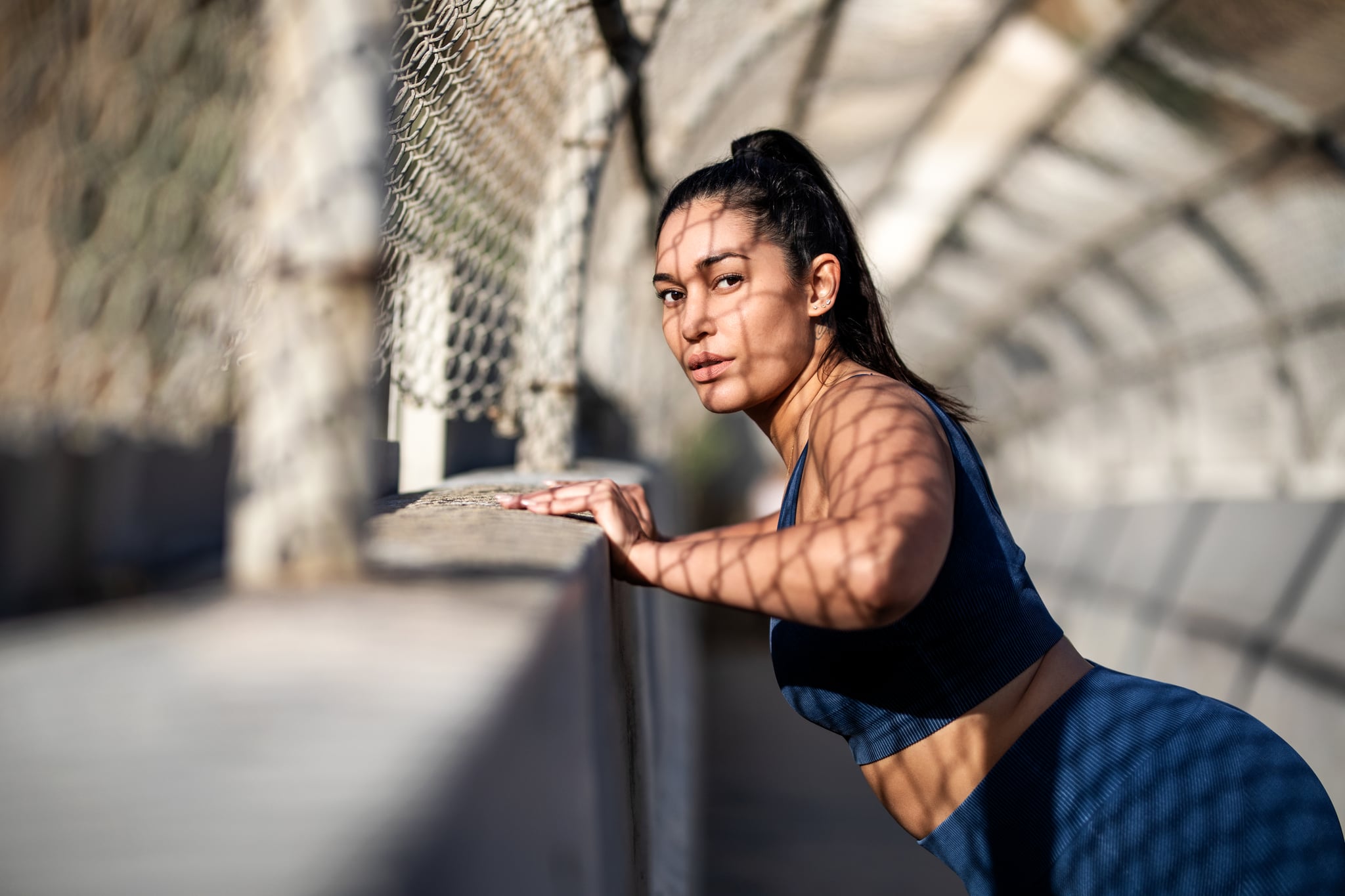 Healthy woman doing push-ups over a concrete wall. Plus size female in sportswear exercising outdoors.