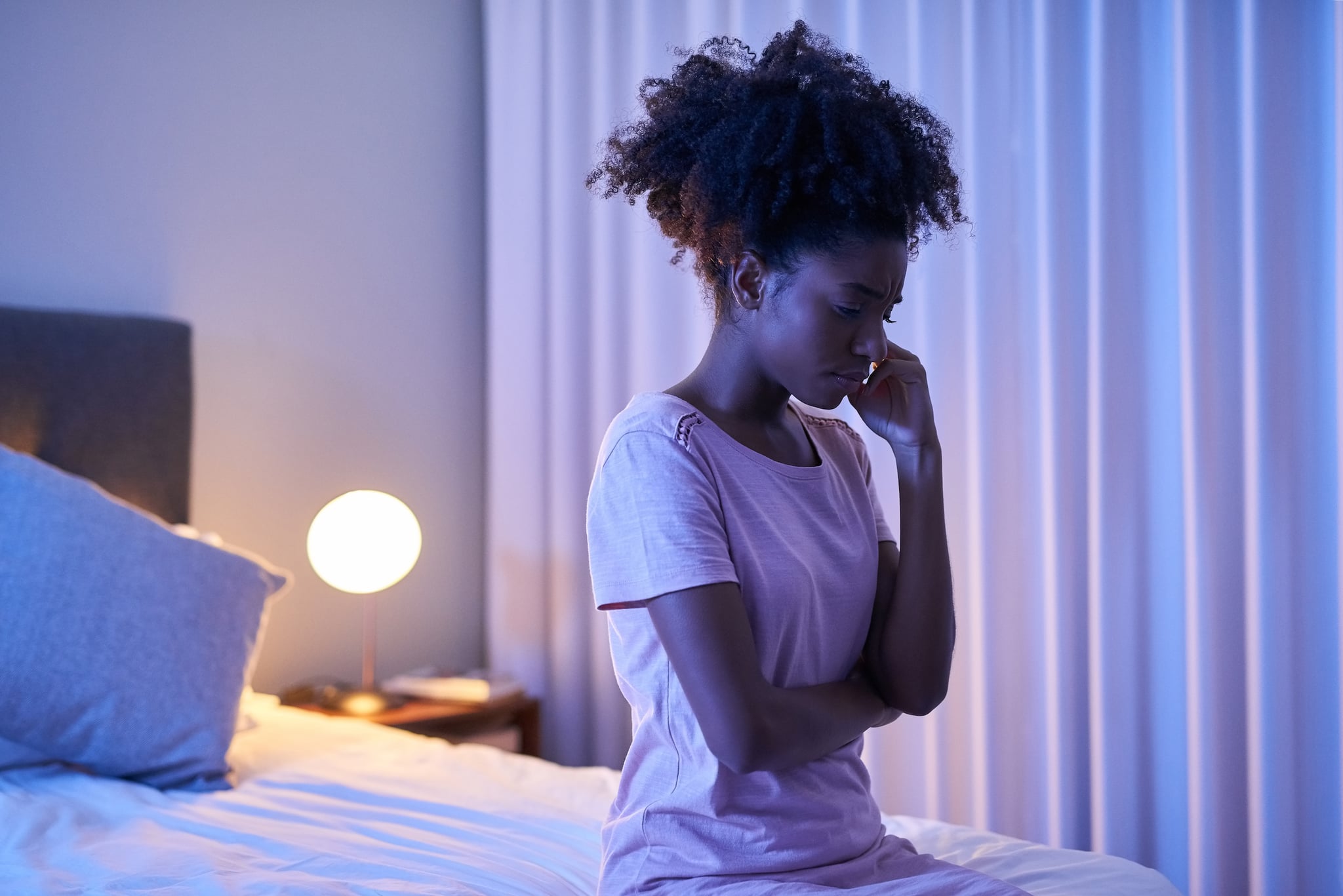 Cropped shot of a young woman sitting alone in her bedroom