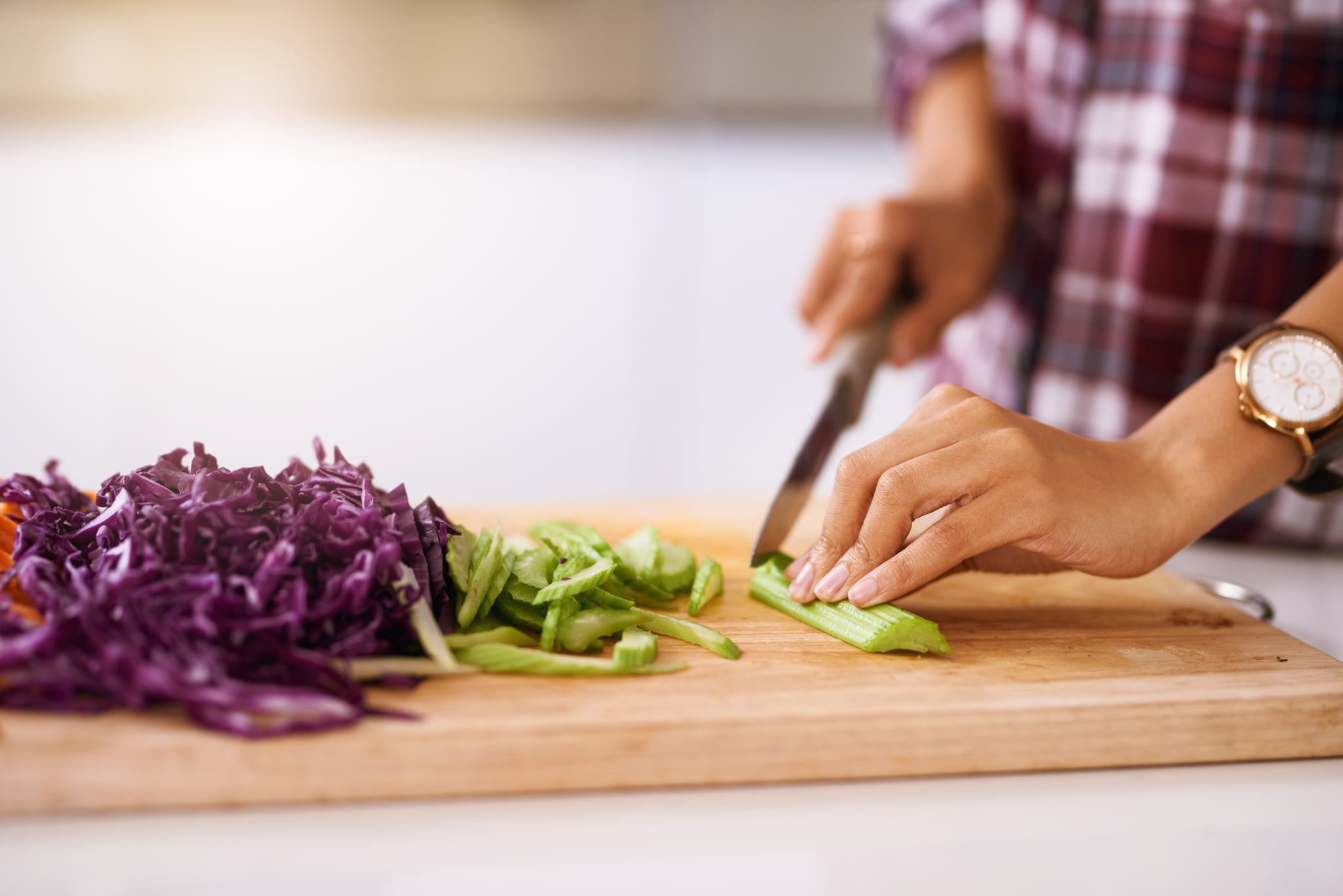 Cropped shot of an unrecognizable woman cutting vegetables in the kitchen at home