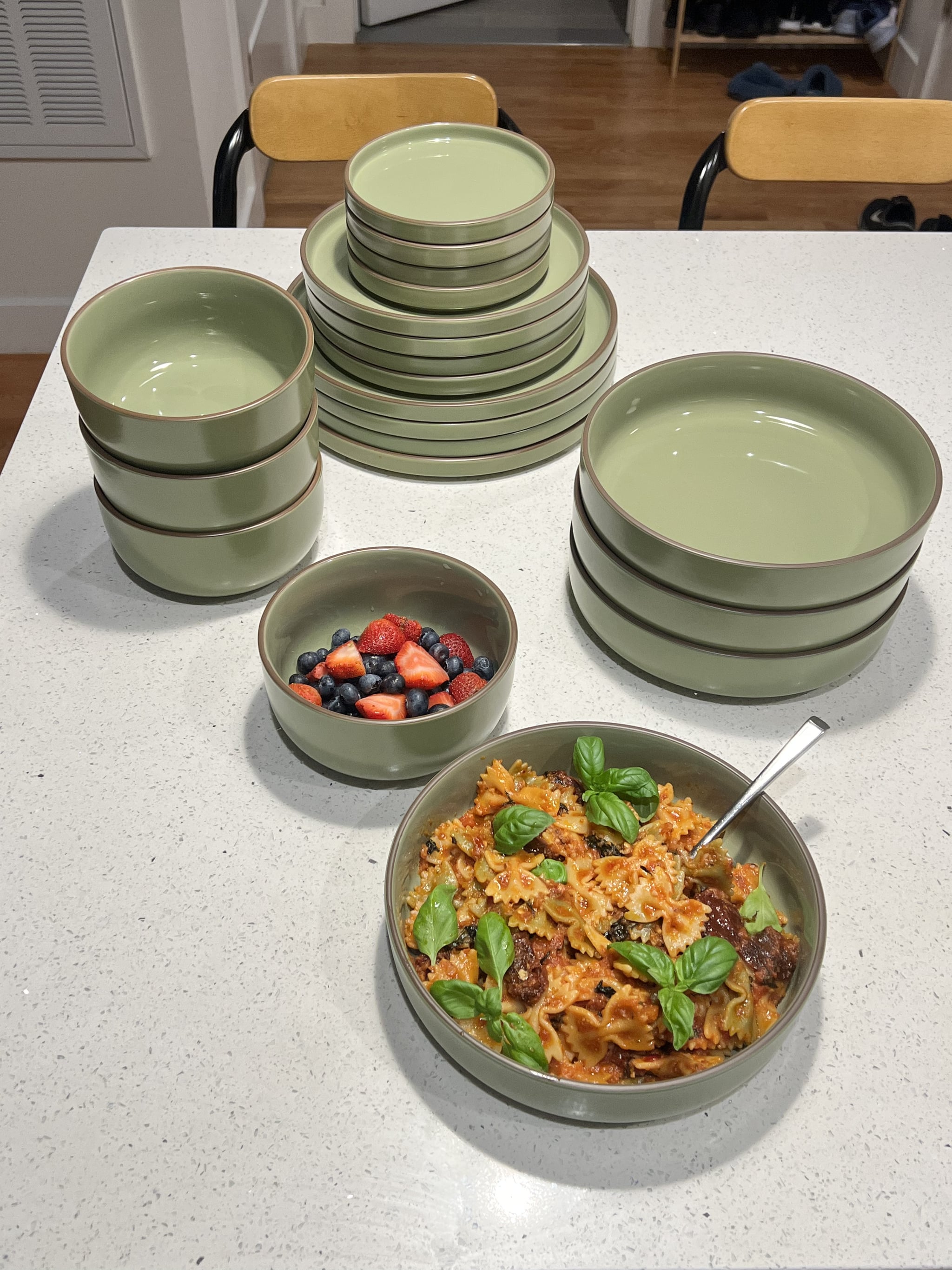The Our Place Classic Stacking Set in Sage with pasta in a big bowl and berries in a small bowl.