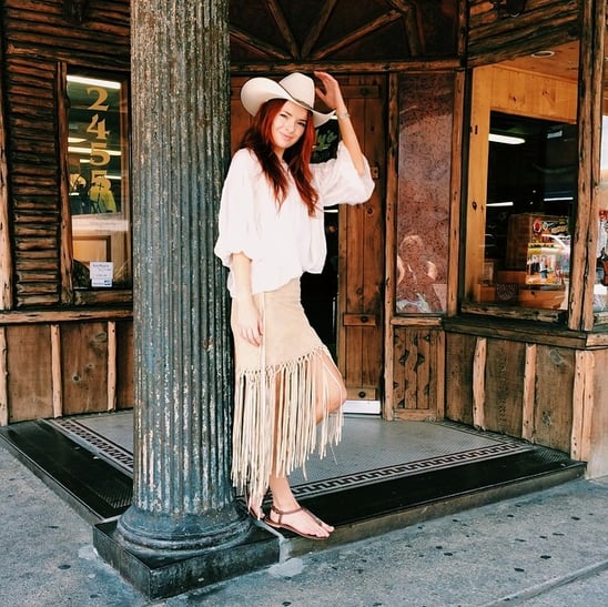 A cowboy hat and fringe give off strong Western vibes, sure, but you can avoid coming off as too costumey with simple sandals and an oversize blouse instead of, say, cowboy boots or a vest.
Source: Instagram user seaofshoes
