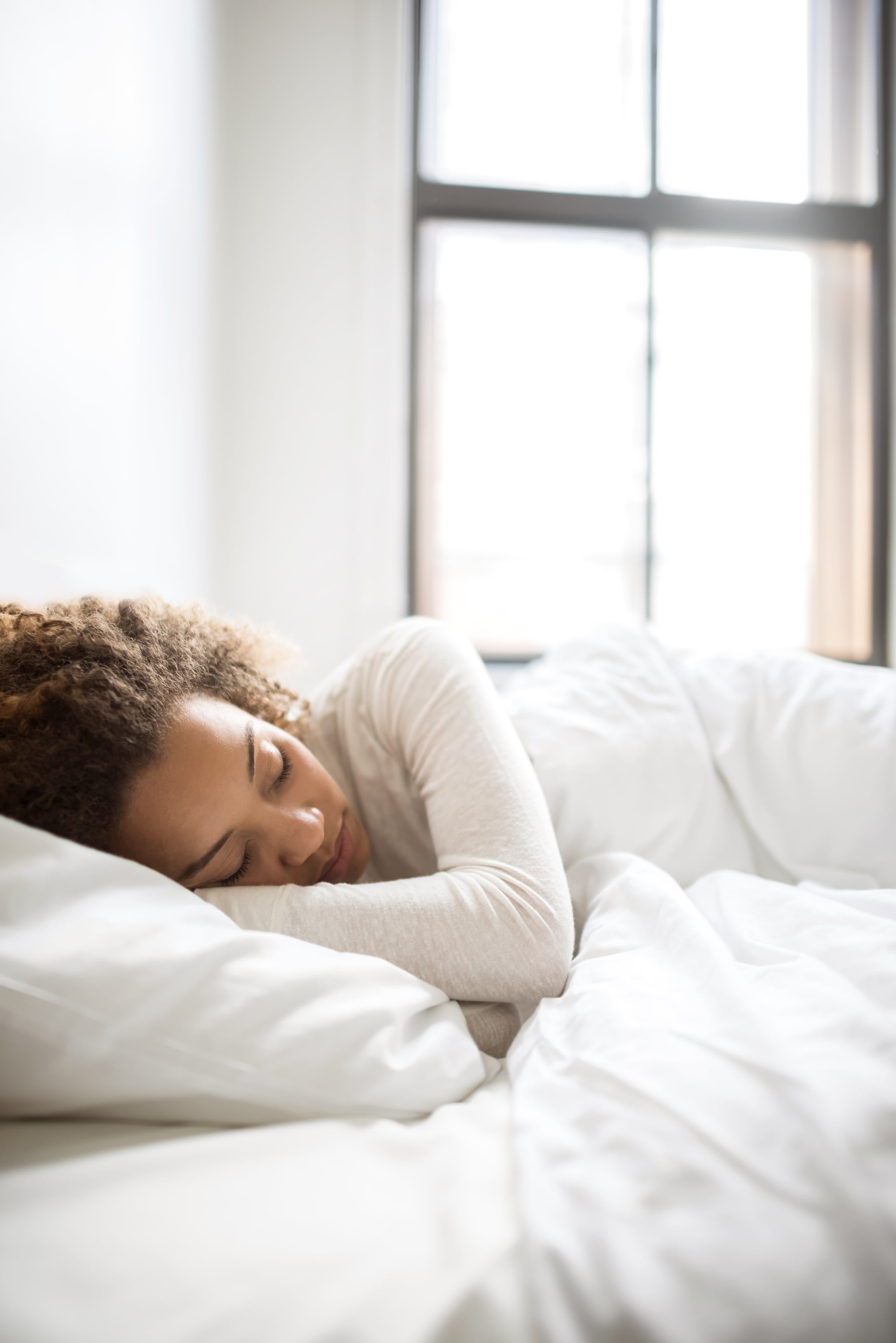 Lazy woman relaxing at home sleeping in her bed