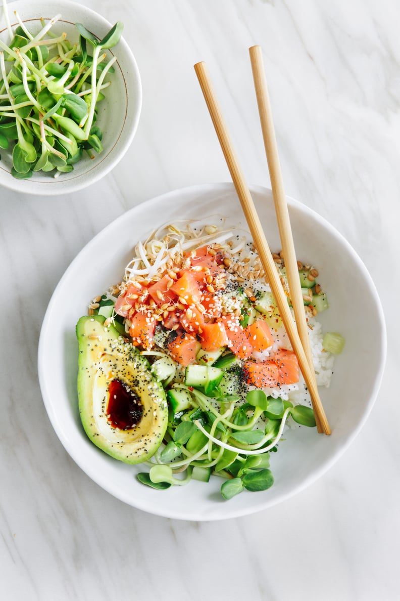 Poke bowls with salmon, avocado, vegetables, sprouts and ponzu dressing on marble background