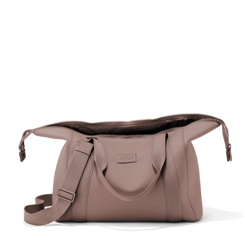 Dagne Dover Landon Large Neoprene Carryall ($170) 
Dagne Dover's Landon Large Neoprene Carryall is soft and durable, perfect for squishing under a seat. It may look compact at first, but it has an expandable design that can fit several outfits, slim shoes and hair tools, and more. 
It comes with plenty of accessories and compartments that will keep your travel essentials organized, like a laptop sleeve, a shoe/laundry bag, and a removable mesh pouch for your chargers and cords. There's even an easy-access pocket perfect for your phone, passport, or boarding pass. 
Plus, it has a crossbody strap, top handles, and two side pockets that are perfect for water bottles and shoes. It comes in nine colors, including black, heather gray, washed lilac, camel tan, navy blue, and a dark moss green.
Pros: Lightweight and great storage space.
Material: Neoprene.
Dimensions: 11" height x 16.5" width x 9" depth
Colorways: 6
Who it's best for: The frequent gymgoer.
Extras: It comes in various sizes, from small to extra large.
What Reviewers Say: "I bring this for every trip. Whether it be a weekend trip or an international one where this can be used as my personal bag. It fits so much and is so chic. Never have I loved a duffel so much."