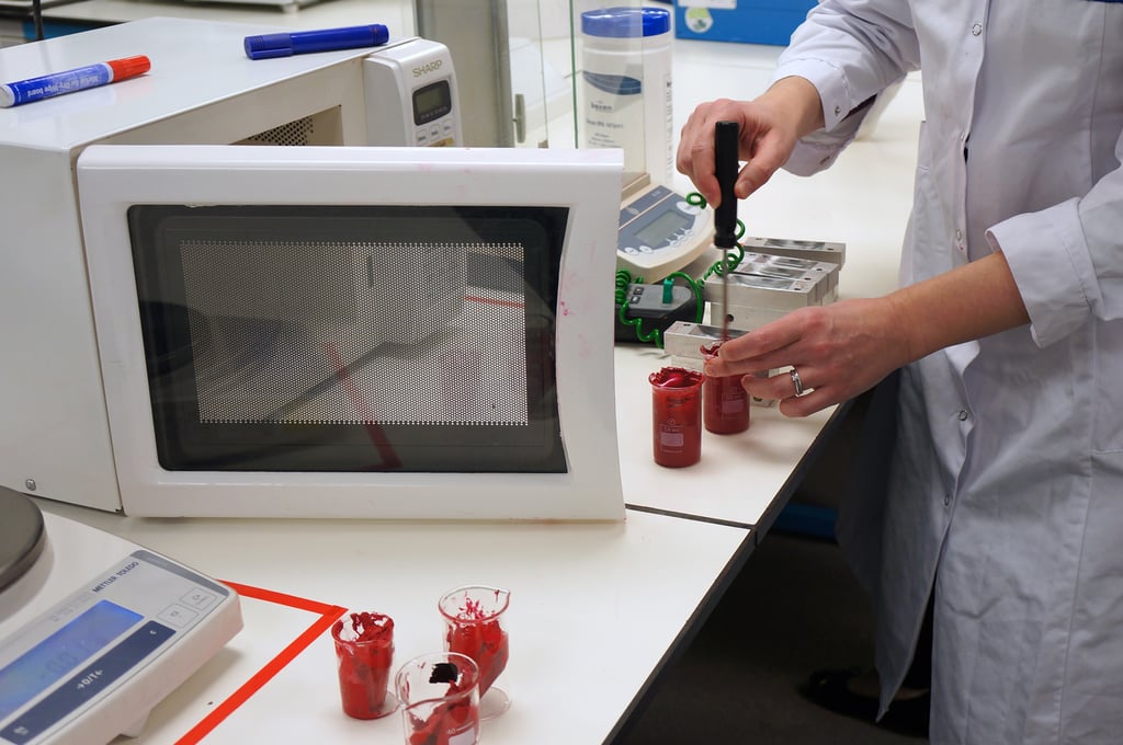 Next up, the lipstick formula is scraped into glass jugs and warmed in a microwave to a high temperature. The lab technicians check the temperature to ensure it's the perfect consistency ready for pouring.