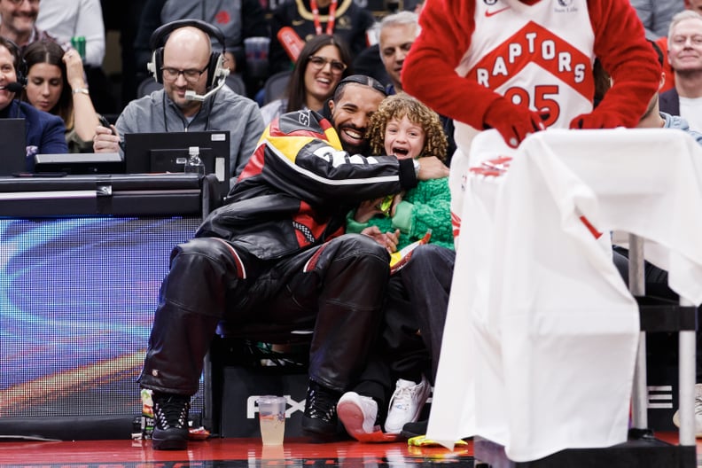 TORONTO, ON - DECEMBER 27: Rapper Drake embraces his son Adonis as the Raptor mascot brings over candy for him during the first half of the NBA game between the Toronto Raptors and the LA Clippers at Scotiabank Arena on December 27, 2022 in Toronto, Canad
