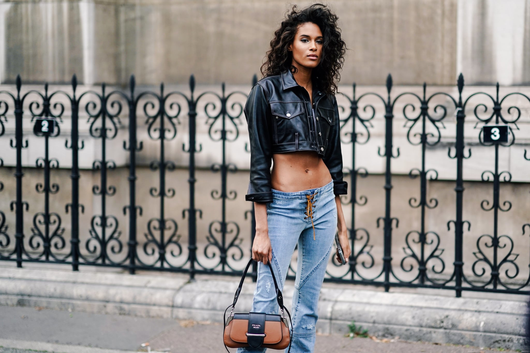 PARIS, FRANCE - FEBRUARY 28: Cindy Bruna wears a black leather crop jacket, blue lace up low waist jeans, a brown Prada bag, outside Redemption, during Paris Fashion Week Womenswear Fall/Winter 2019/2020, on February 28, 2019 in Paris, France. (Photo by Edward Berthelot/Getty Images)