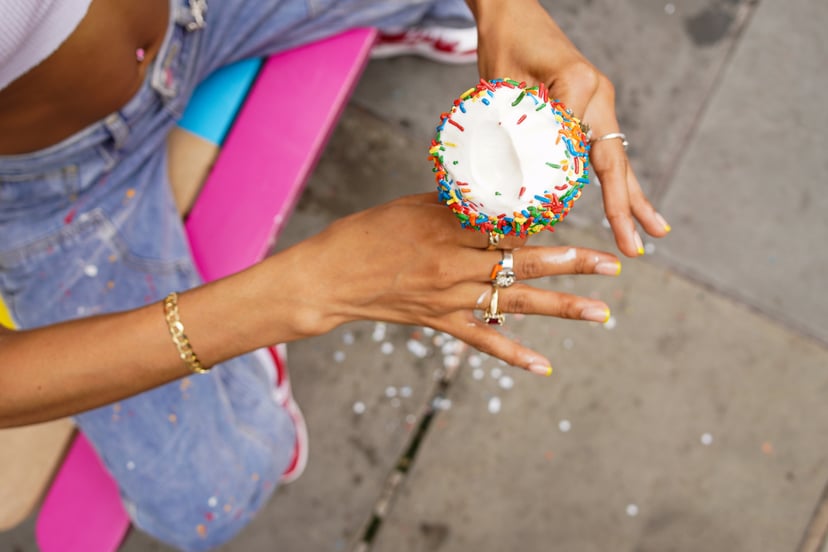 A creative portrait of a Woman holding a Ice Cream Cone with Rainbow Sprinkles to symbolize birthday freebies