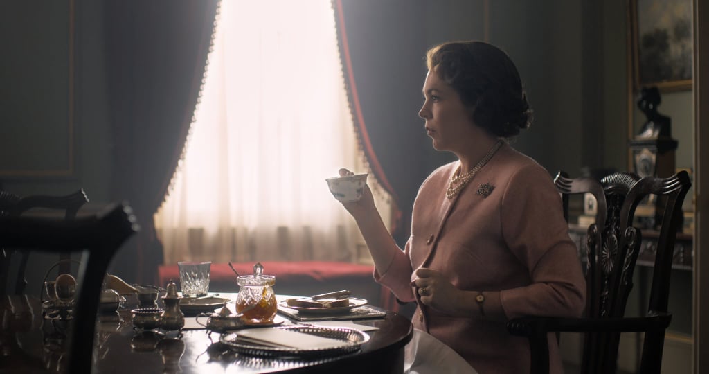 It's officially a new chapter of The Crown. On Monday, Netflix released the first look at Olivia Colman as Queen Elizabeth II for season three. The English actress will be taking over for Claire Foy, who played the iconic role for the first two seasons. Wearing a pink jacket fit for royalty, the image showcases Colman giving a stern look while sipping on a cup of tea.
Colman isn't the only new cast member for the upcoming season. Since season three will take place in the late '60s and into the late 1970s, the series is replacing the main cast with new, older actors to more accurately portray the passing of time. In addition to casting Tobias Menzies as Prince Philip and Helena Bonham Carter as Princess Margaret, the upcoming season will introduce Princess Diana, though there hasn't been an official confirmation on who will be play the late royal just yet.