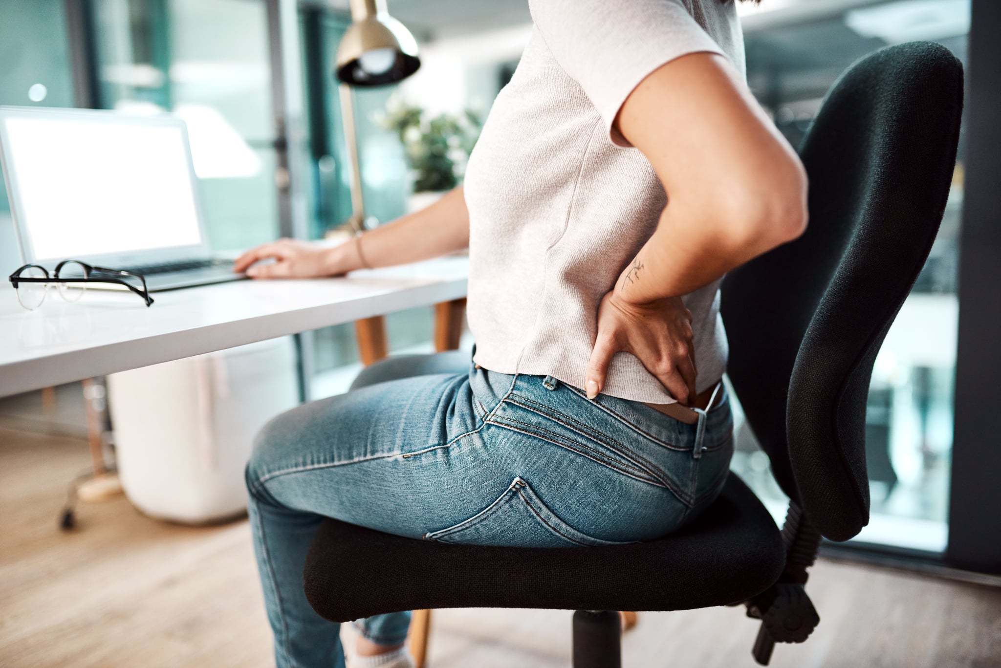 Closeup shot of an unrecognisable businesswoman experiencing back pain while working in an office
