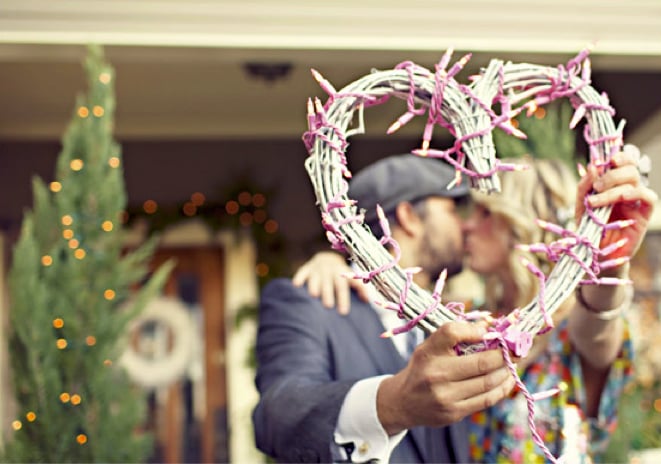 Kiss in Front of a Heart Made of Christmas Lights