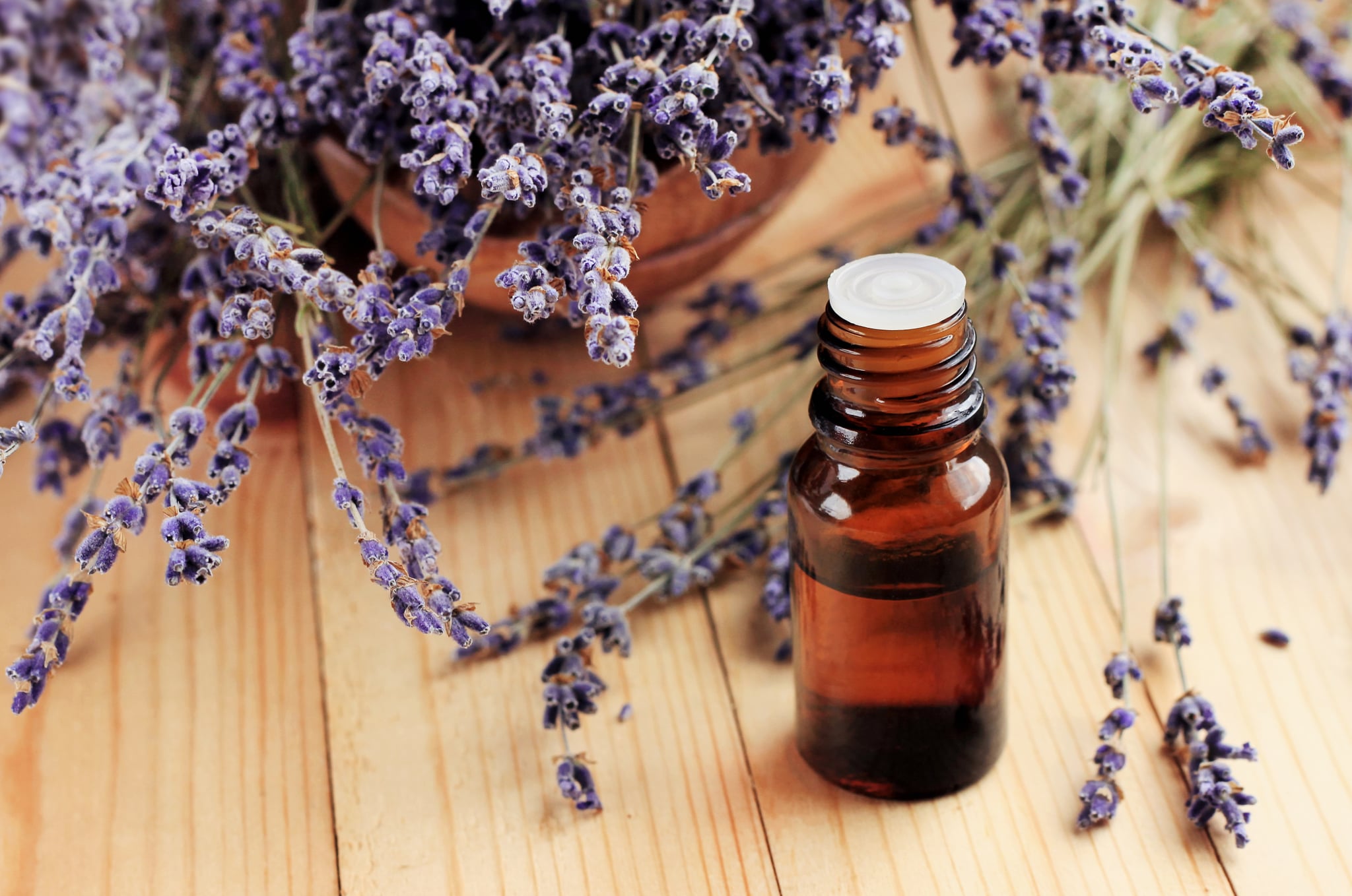 Dried purple plant flowers, dark glass dropper bottle, wooden table. Natural aromatherapy.