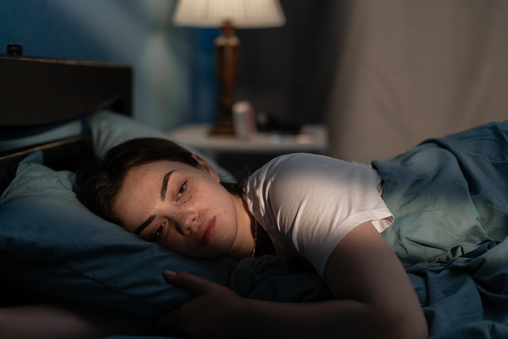 Woman lying in bed late at night trying to sleep suffering from night sweats.