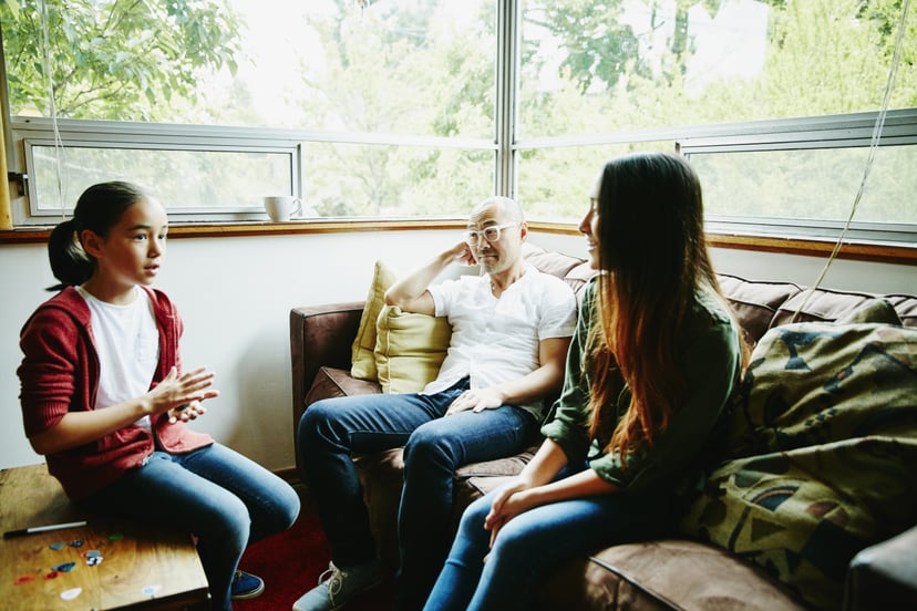 Father in discussion with daughters in living room before school