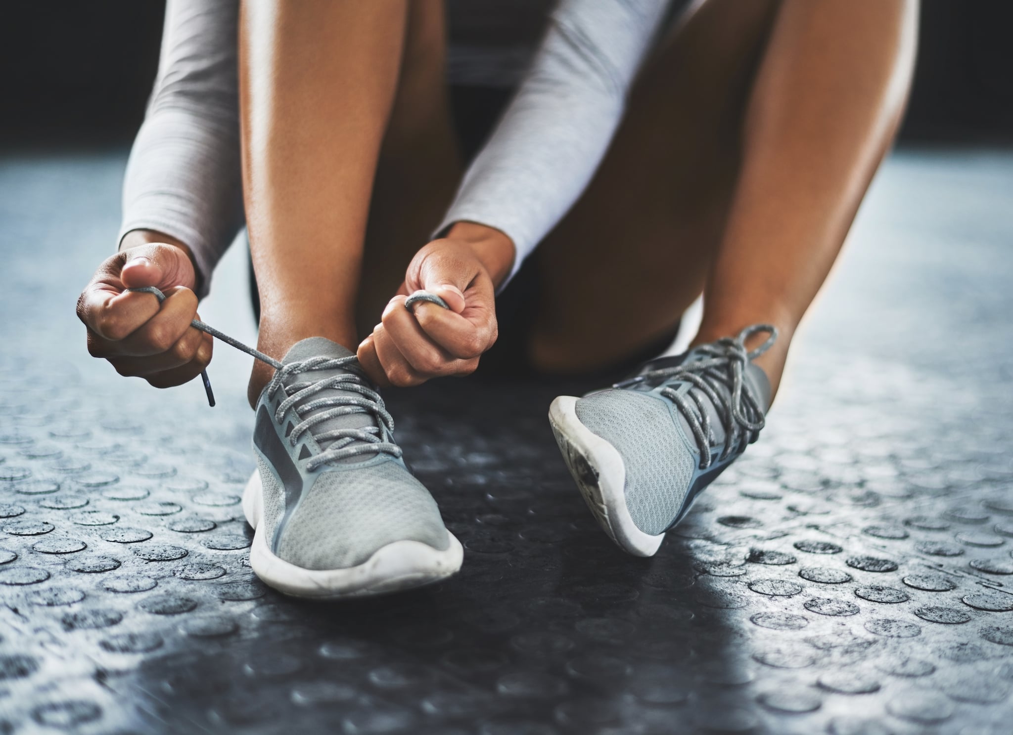 Cropped shot of a woman tying her shoelaces in a gym