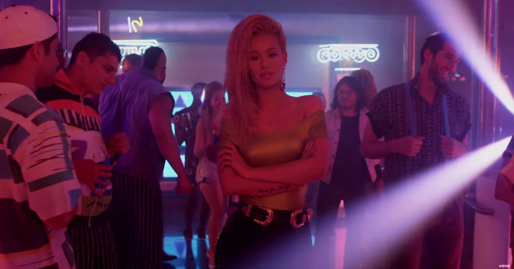 Iggy in the club, in a gold top, black pants, a double-buckled belt (interesting . . . ), and some drop earrings.