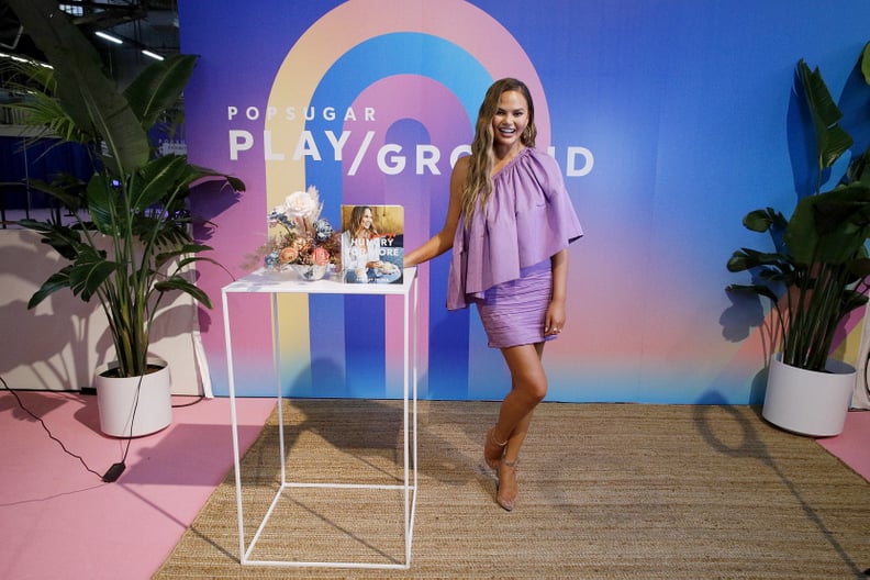 NEW YORK, NEW YORK - JUNE 23: Chrissy Teigen poses with her cookbook during POPSUGAR Play/Ground at Pier 94 on June 23, 2019 in New York City. (Photo by Lars Niki/Getty Images for POPSUGAR and Reed Exhibitions )