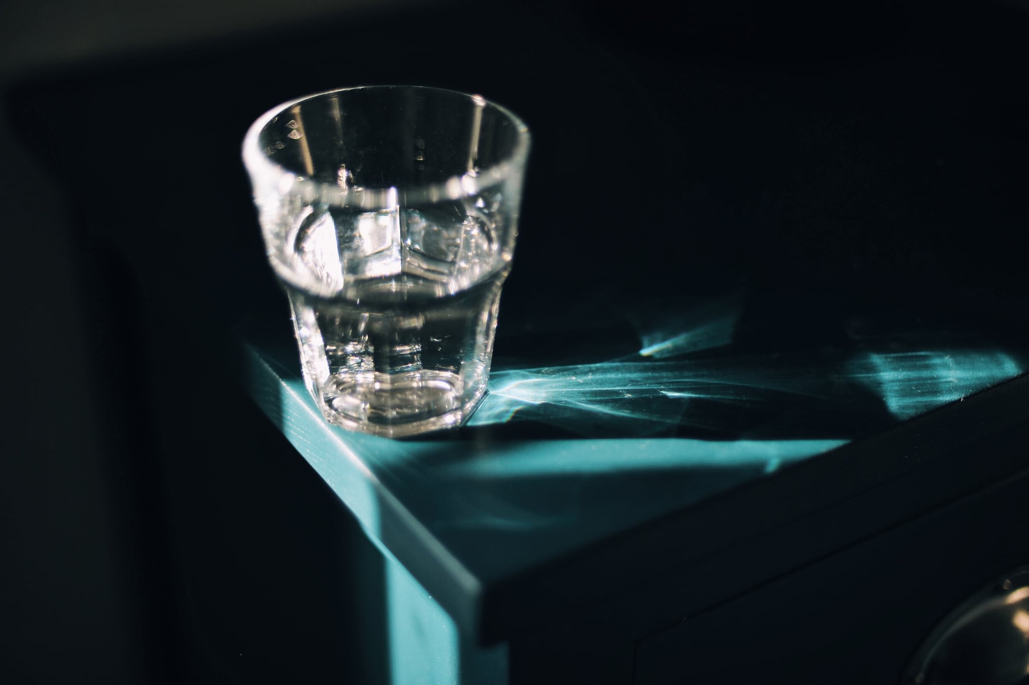 Glass of water in strong sunlight on bedside table