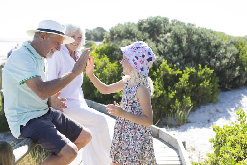 Senior couple, aged 70-75, playing outdoors with their grandchildren